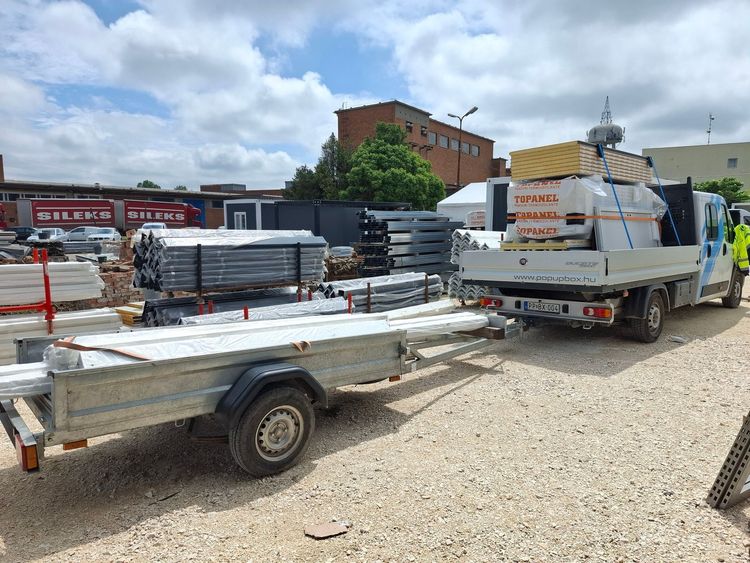 Konténer elemek szállítása utánfutón, szendvicspanelek és moduláris épületelemek logisztikai mozgatása